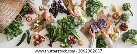 Female hands cutting various veggies and fruits, top view