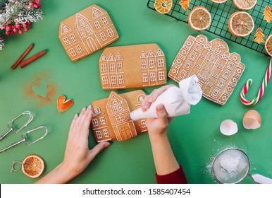 Female Hands Decorating Christmas Gingerbread Cookies House. Top View, Flat Lay. 