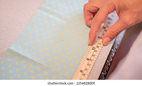 Female hands of the designer at work with fabric close-up. The tailor measures the necessary amount of material for sewing cloth.  - Shutterstock ID 2256828009