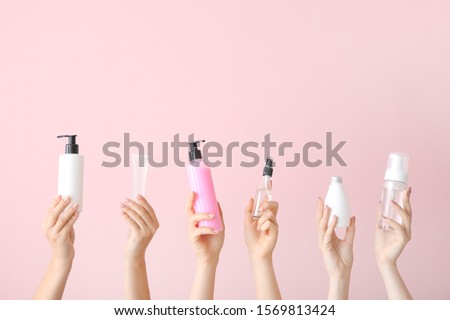Female hands with different cosmetic products in bottles on color background