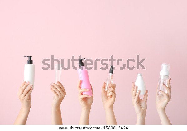 Female hands with different cosmetic products\
in bottles on color\
background