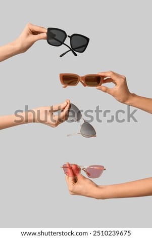 Female hands with different stylish sunglasses on grey background