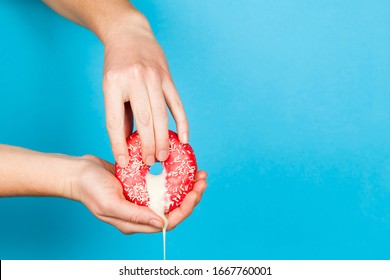 Female hands and a donut on a blue background as a symbol of masturbation and foreplay (prelude) before sex. Touch the clitoris, erotic concept.
