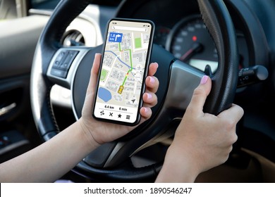 female hands driving car holding phone with navigator app on the screen