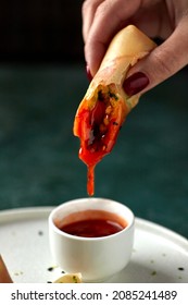 Female Hands Dunk Spring Roll In Hot Sauce, Asian Food