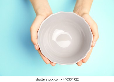 Female Hands And Empty Bowl On Turquoise Background