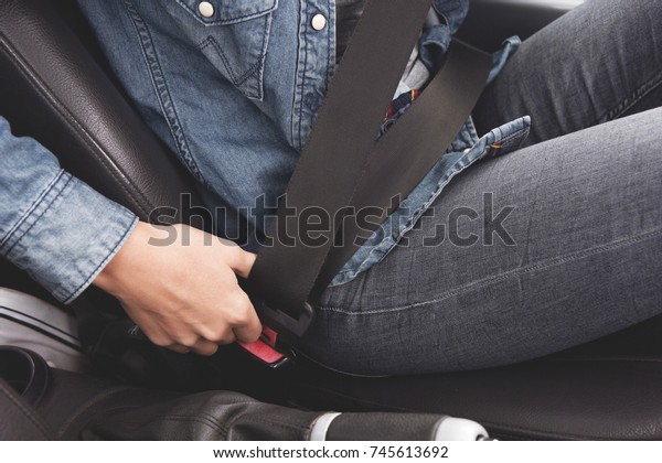 Female hands\
fasten the seat belt in the\
car.