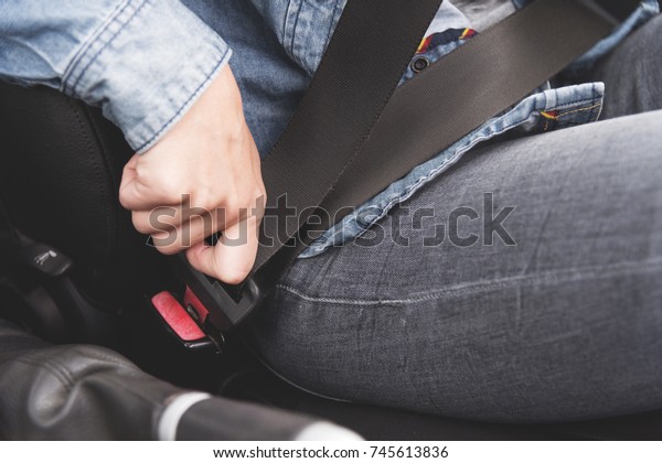 Female hands\
fasten the seat belt in the\
car.