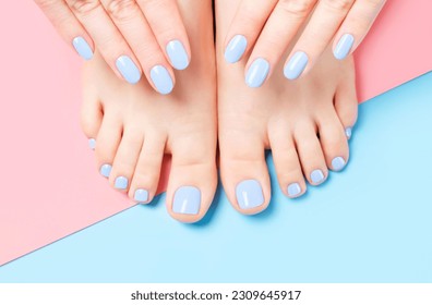 Female hands and feet with light blue manicure and pedicure on a blue and pink background top view close up. - Powered by Shutterstock