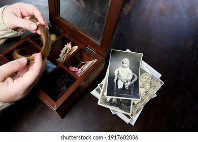female hands fingering memorabilia in an old wooden box, a stack of retro photos, a lock of hair, vintage photographs of 1960, concept of family tree, genealogy, childhood memories