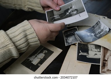 female hands fingering old photographs of 1950s, stack of photos on the table, concept of genealogy, memory of ancestors, family tree, nostalgia, childhood, remembering - Shutterstock ID 2034072107