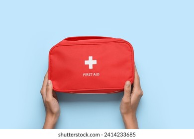 Female hands with first aid kit on blue background