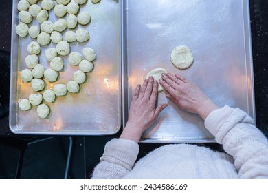 Female hands flattening dough balls and shaping it in circles to be stuffed later, dough hand made - Powered by Shutterstock