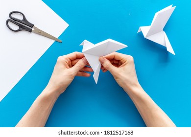 Female Hands Folding Sheet Of Paper - Origami Bird. Overhead View