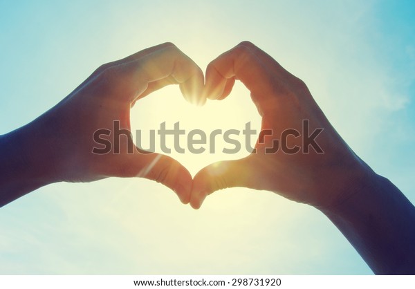 空に向かって心臓の形をした女性の手が太陽の光を通り過ぎる 愛の心の形をした手 の写真素材 今すぐ編集