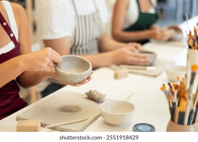 Female hands forming plate from wet clay in a pottery workshop