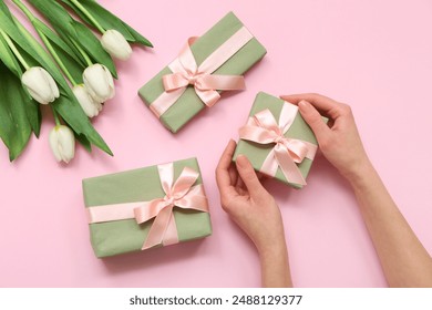 Female hands with gift boxes and beautiful white tulips on pink background. International Women's Day - Powered by Shutterstock