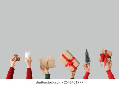 Female hands with gift boxes and mini Christmas tree, letter, glass of milk and cookies on grey background - Powered by Shutterstock