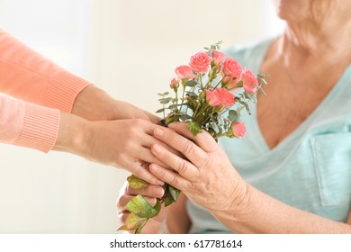 Female Hands Giving Flowers To Old Woman