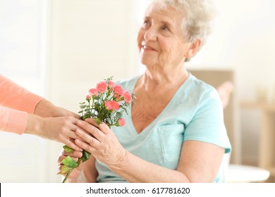 Female Hands Giving Flowers To Old Woman