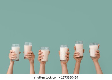 Female hands with glasses of vegan milk on color background