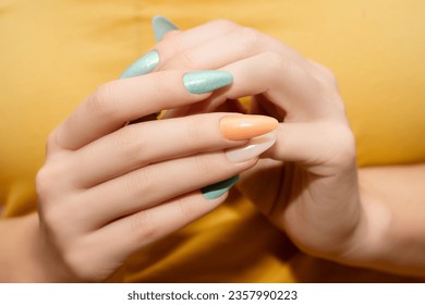 Female hands with glitter nail polish. Green and orange nail design with two shades. Women hands with sparkle colored manicure