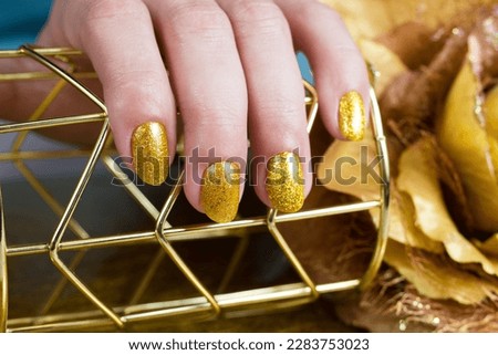 Female hands with a gold colour nails. Nail design. Artistic manicure with gel polish