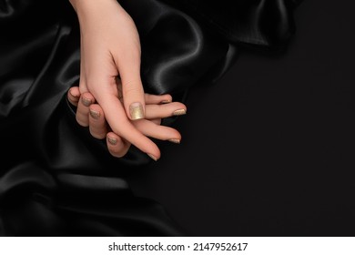 Female Hands With Golden Nail Design. Glitter Gold Nail Polish Manicure. Female Model Hands With Perfect Manicure On Black Fabric Background. Copy Space.