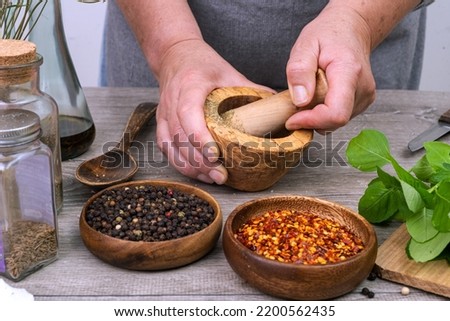 female hands grind spices in a mortar on the kitchen table.