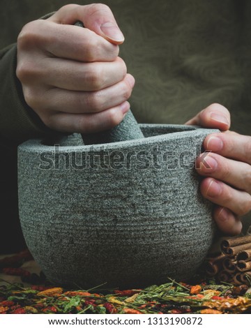Female hands grinding spices in mortar. Chili peppers and cinnamon on the table