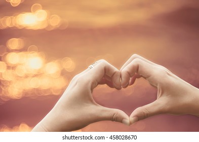 Female hands heart shape on nature bokeh sun light flare wave and blur tropical beach abstract background. Copy space of happy love travel and freedom in nature concept. Vintage tone color style. - Shutterstock ID 458028670
