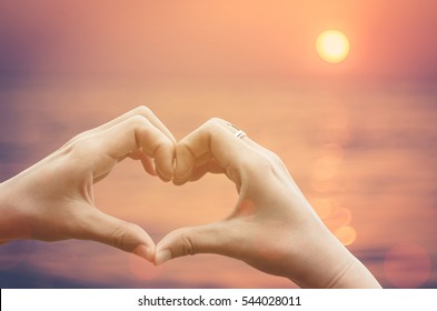 Female hands heart shape on nature bokeh light flare wave and blur tropical sunset beach abstract background. Copy space of happy love travel and freedom in nature concept. Vintage tone color style.  - Shutterstock ID 544028011