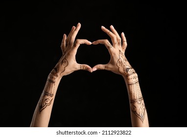 Female Hands With Henna Tattoo Making Heart On Dark Background