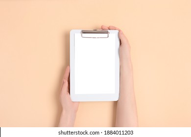 Female hands hold blue clipboard. Clean mockup on a beige background.