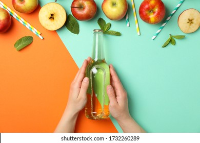 Female hands hold bottle of cider on two tone background. Composition with cider