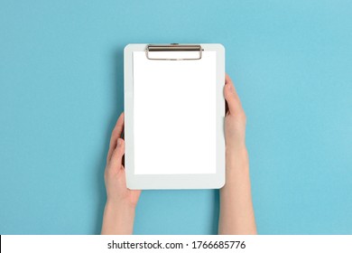 Female hands hold clipboard. Empty mockup on a blue pastel background.