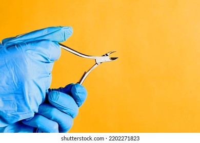 Female Hands Hold Cuticle Nipper Over Yellow Background