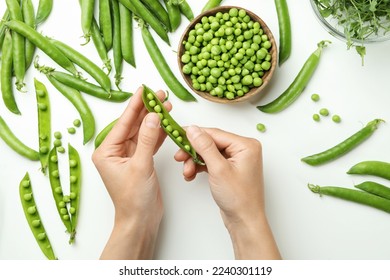 Female hands hold green pea on white background, top view