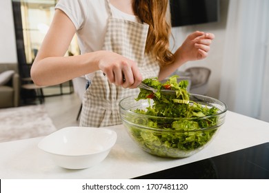 Female Hands Hold Green Salad With Tongs