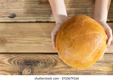 Female Hands Hold A Loaf Of Bread Over A Wooden Store Counter. A Traditional Bakery With Many Generations Of Experience.