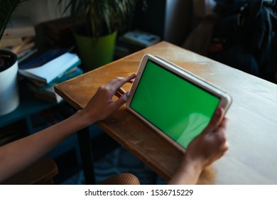 female hands hold a tablet with a green screen on a table in a cafe. mock up