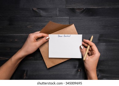 Female Hands Holding Ballpoint Over The Gift Card Lying On The Black Wooden Table