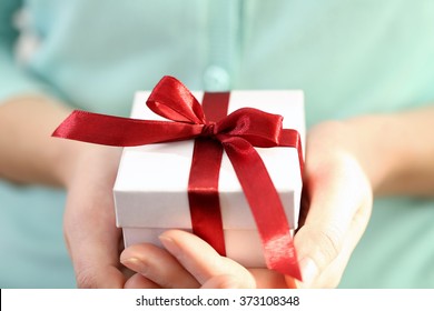 Weibliche Hände, die schöne kleine Geschenk verpackt mit Satinband.
