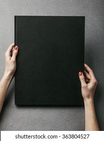 Female hands holding big black book. Vertical
