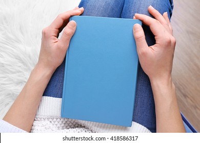 Female Hands Holding A Blue Book.