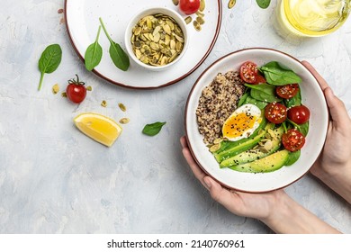 Female hands holding bowl with avocado, egg, tomatoes, spinach and sunflower seeds on a light background. Homemade food. Healthy, clean eating. Vegan or gluten free diet, place for text, top view. - Powered by Shutterstock