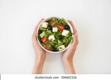 Female Hands Holding Bowl With Green Lettuce Salad Isolated On White