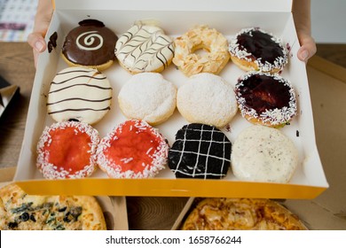 Female hands holding box with colorful donuts, ready for party.