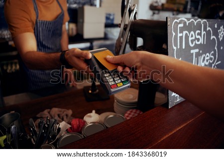 Female hands holding card against nfs payment machine to make payment for purchase in cafe