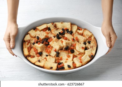 Female Hands Holding Casserole Dish With Baked Bread Pudding On Wooden Table